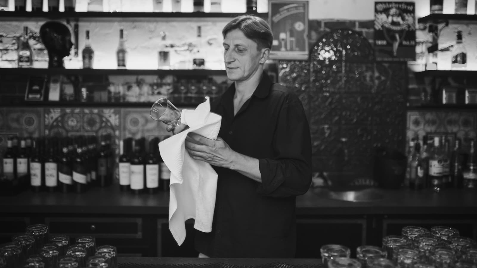 Bartender polishing a glass in vintage-style bar interior